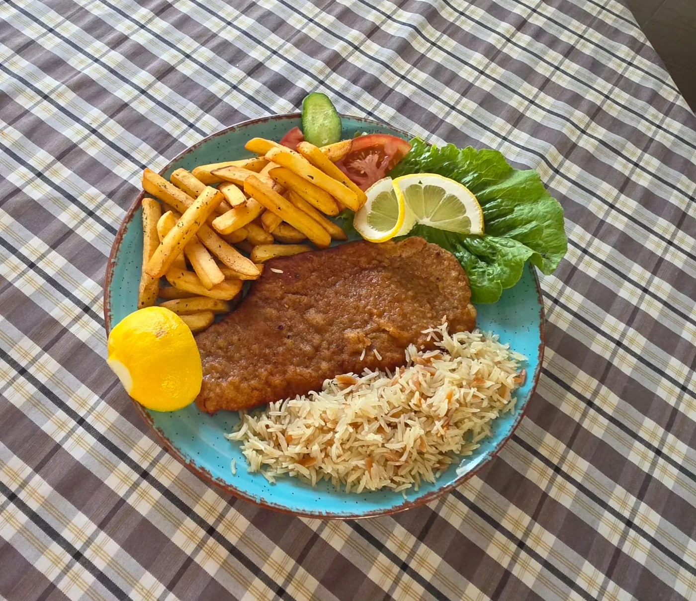 Breaded schnitzel with fries, rice and lemon